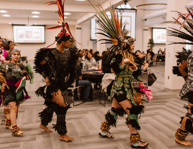Members of a native tribe dressed in Aztec attire perform a traditional dance.