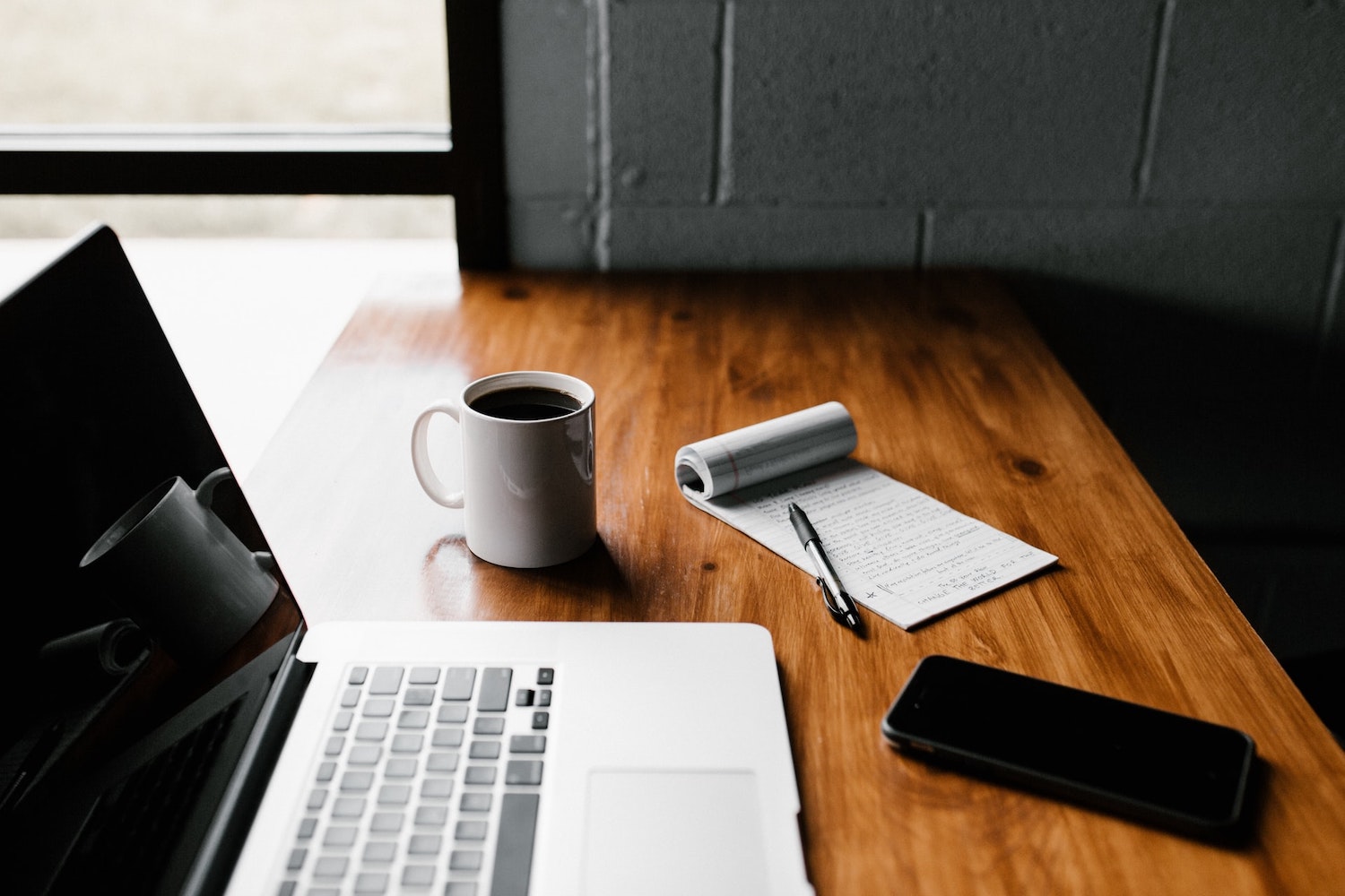 computer on desk with notepad and cup of coffee