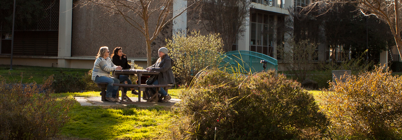Three people sitting at a table outdoors.