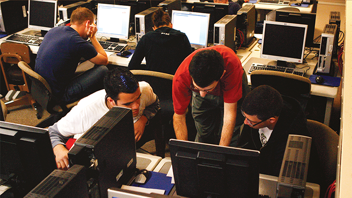 Estudiantes de tecnología trabajando juntos en el laboratorio de computación.