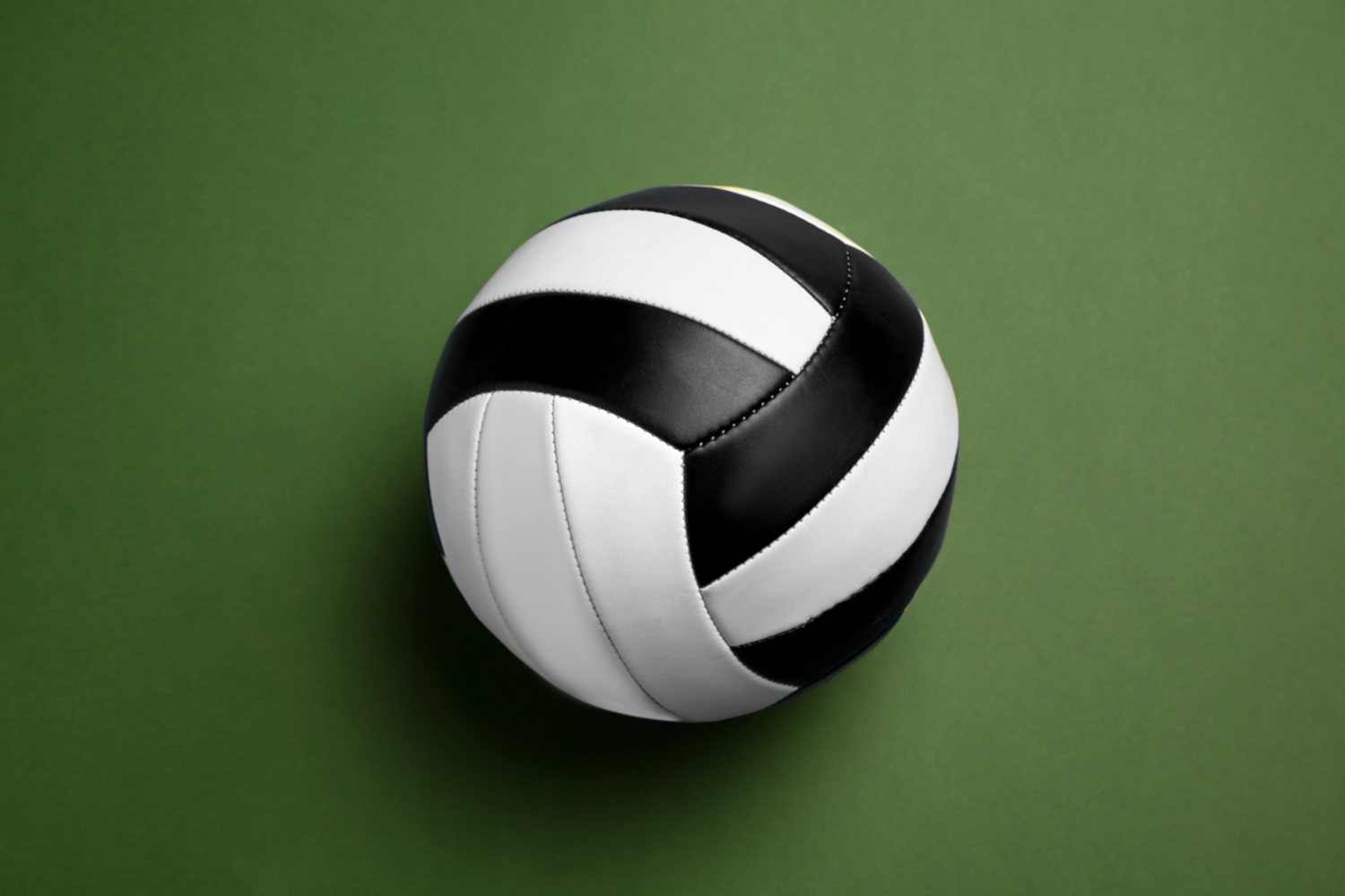 A black and white volleyball. Green background 