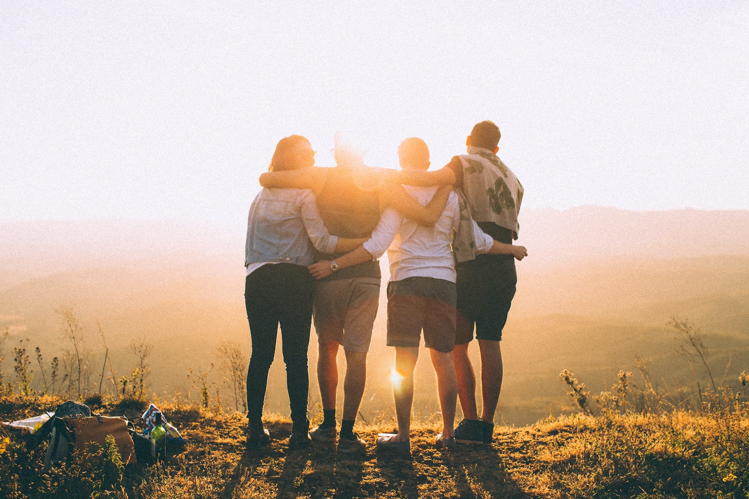 Group of people hugging in front of a sunset