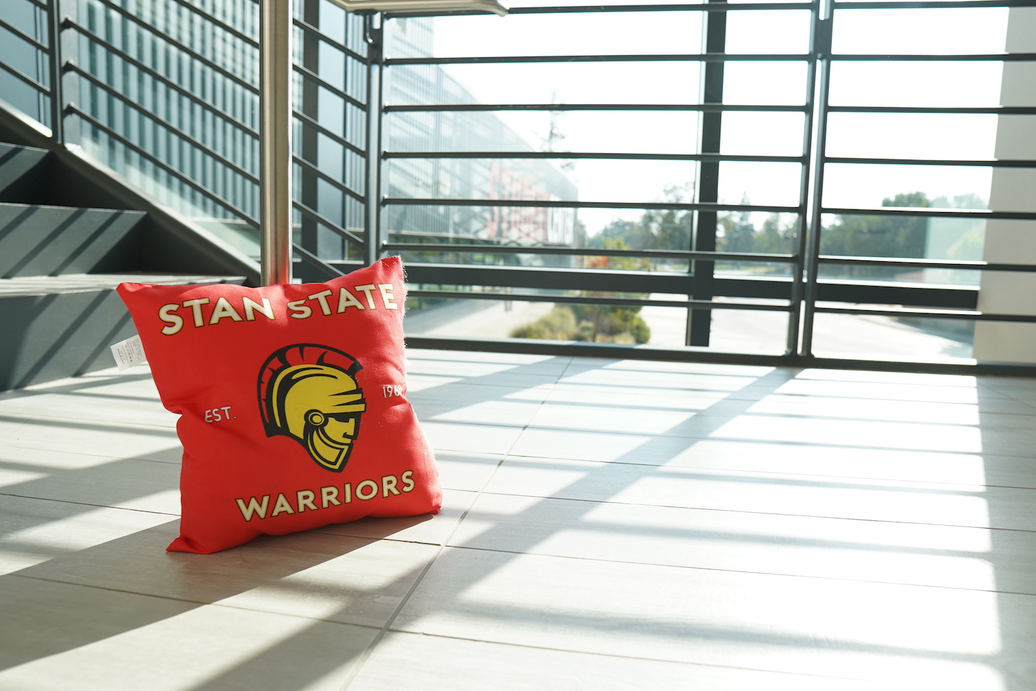 A pillow with the Stan State Warrior symbol is set by the window
