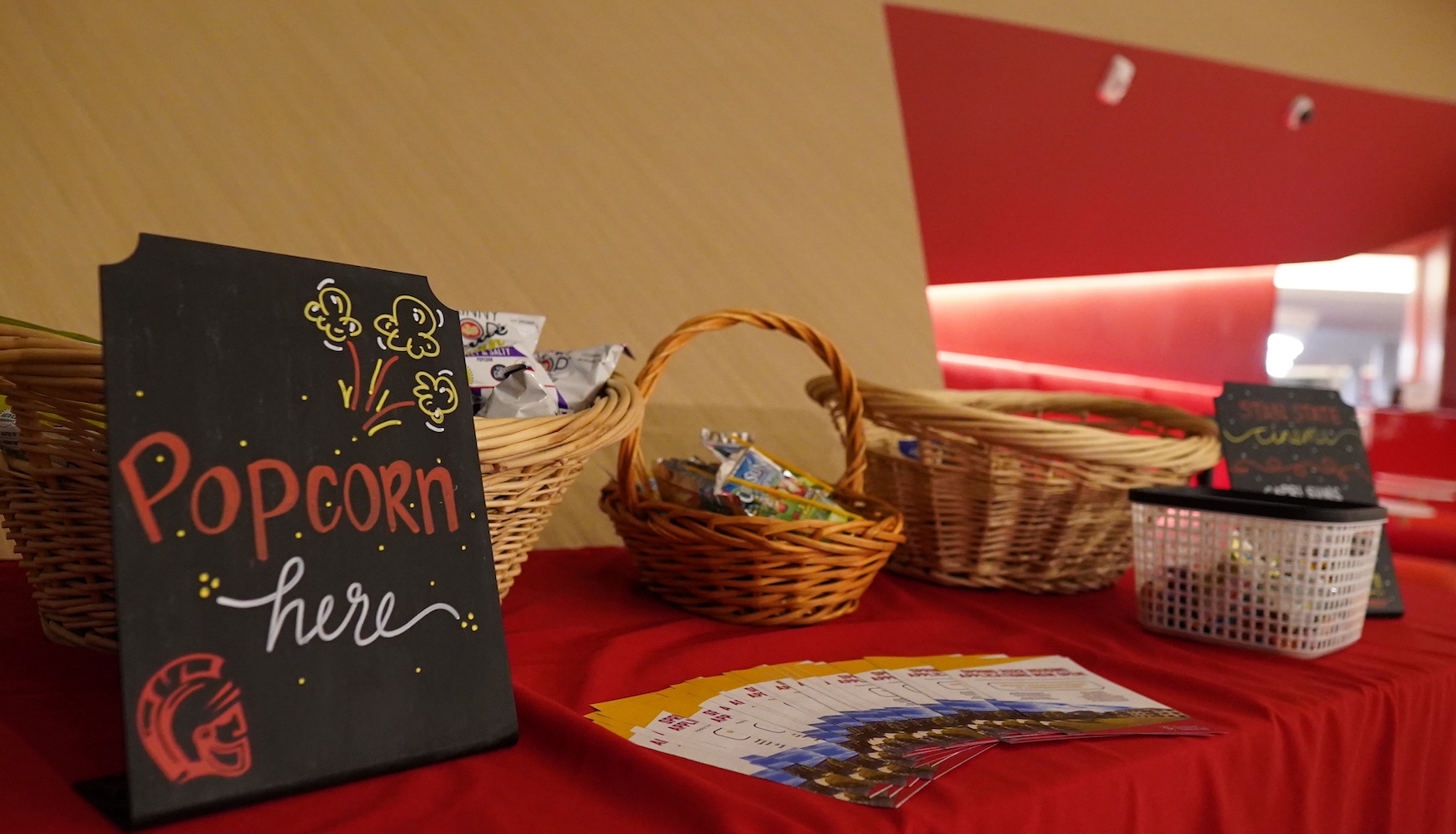 Table with small baskets filled with snacks, sign that reads "Popcorn here"