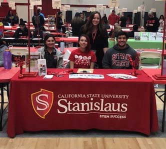 nso_crop.jpg Group of three students sitting behind Stanislaus State booth with one student standing behind