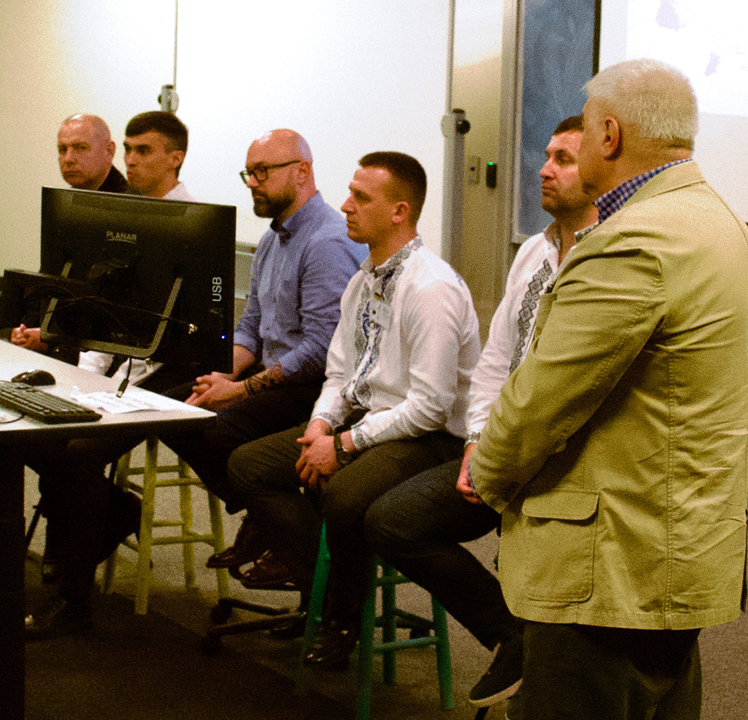 Visitors from the Ukraine sit in front of a classroom and give a pressentation.