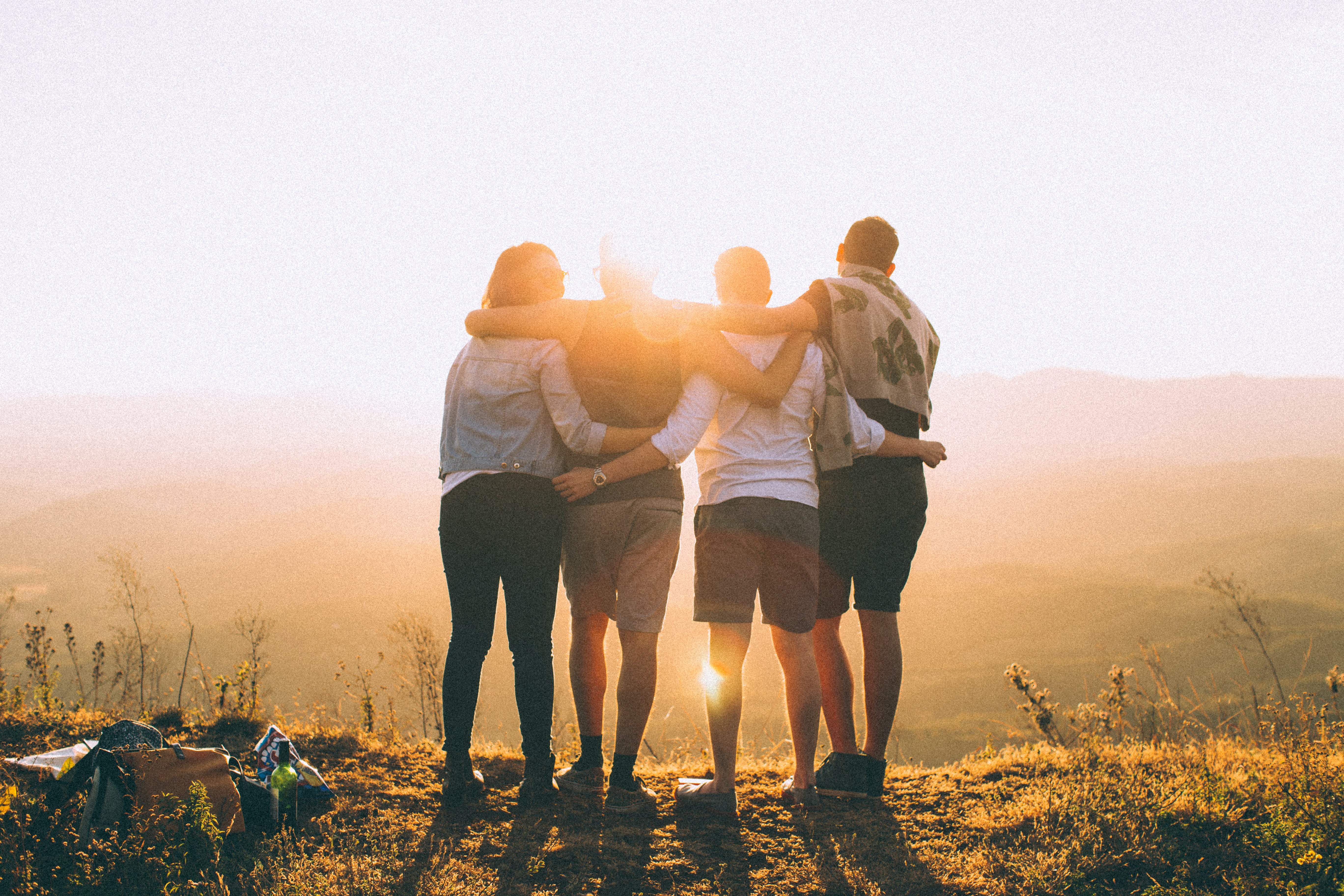 four people hugging watching the sunset 