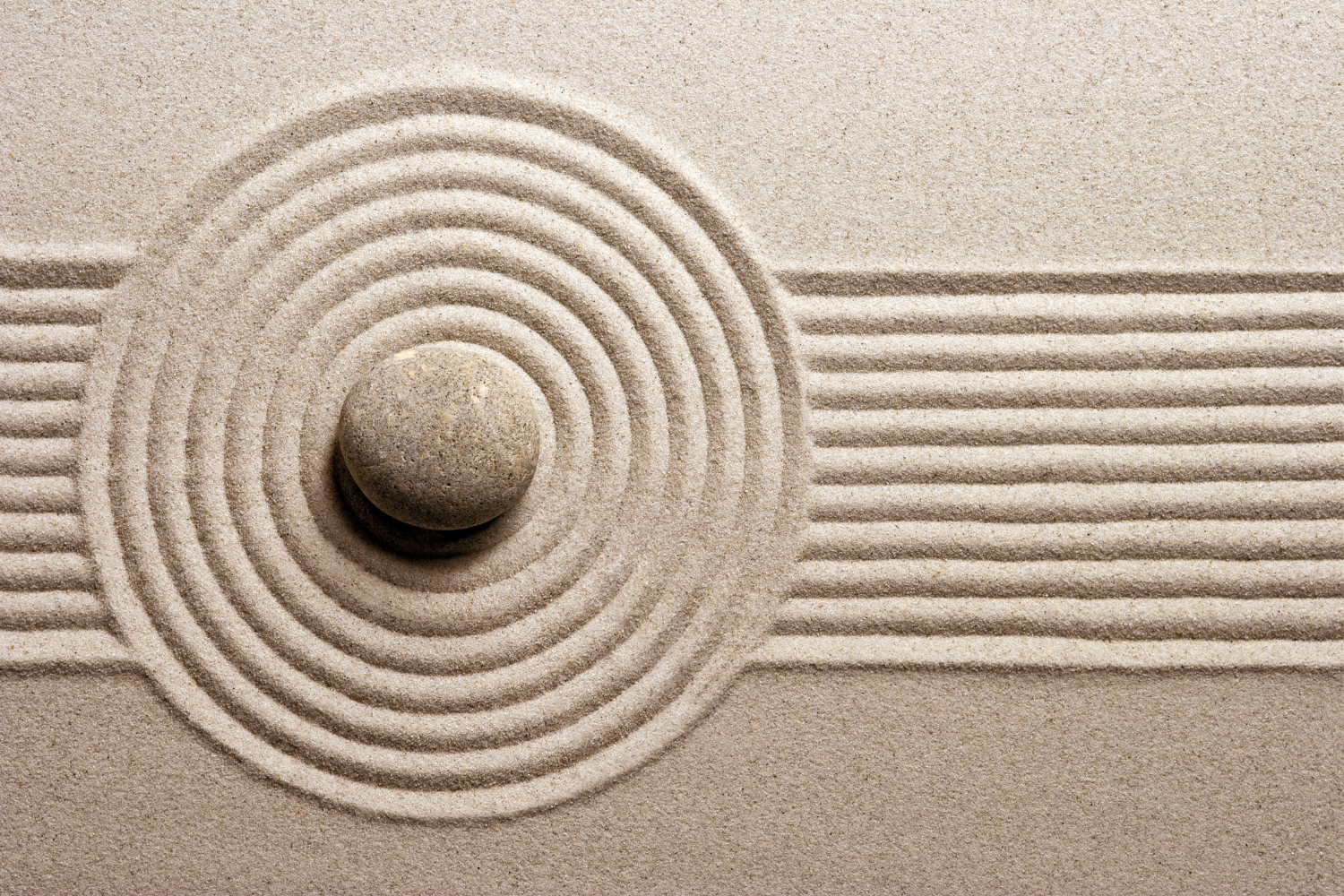 a zen garden of sand with a rock in the center