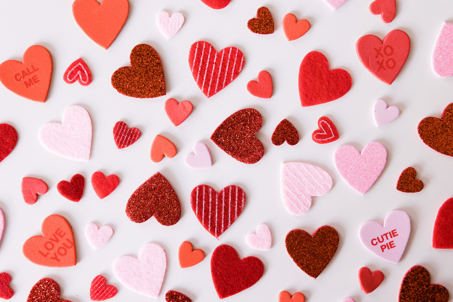 various Valentine Sweetheart heart shaped candies spread across a white background. 
