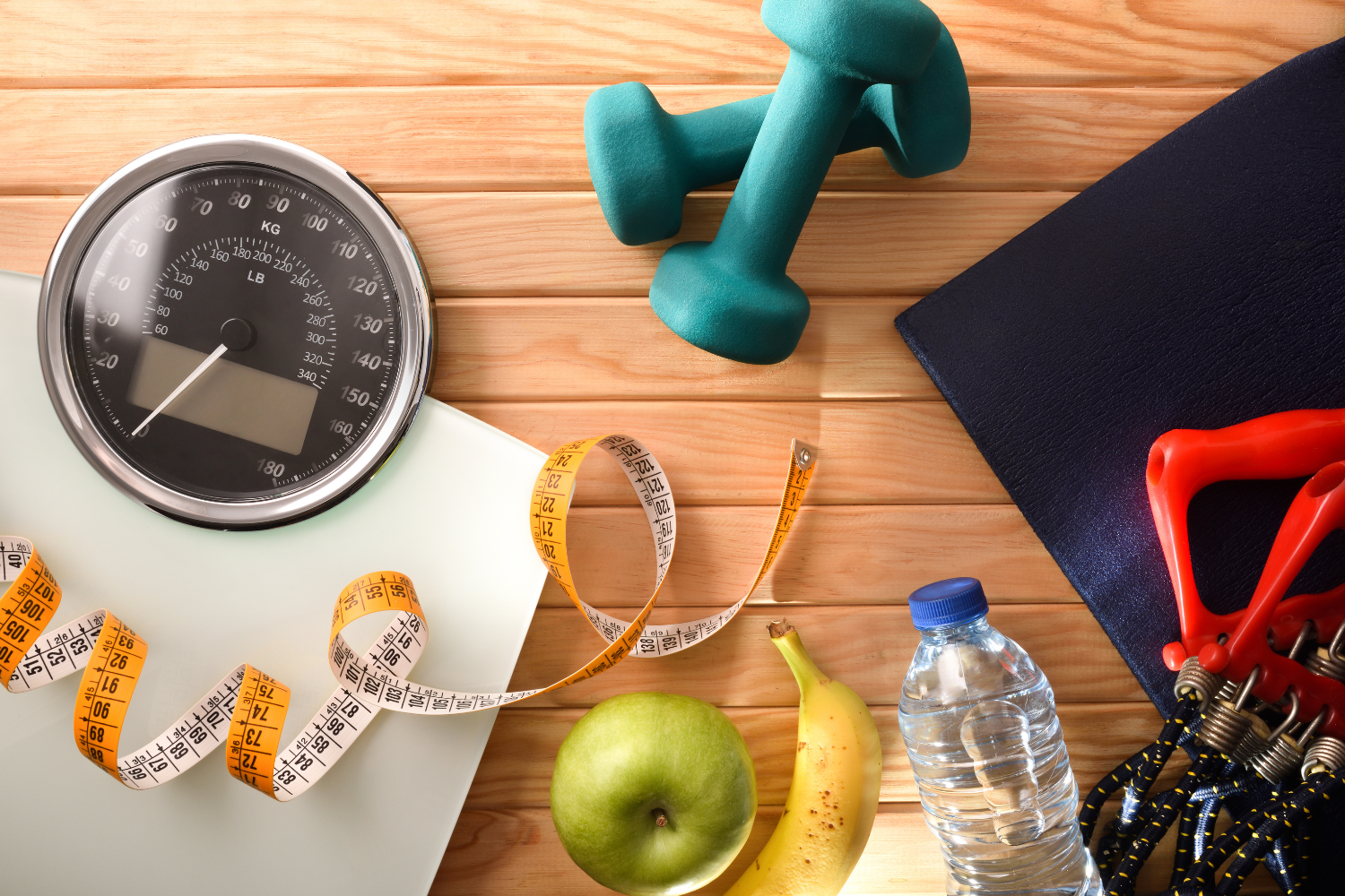 a scale, measuring tape, and weights referring to a healthy lifestyle. 