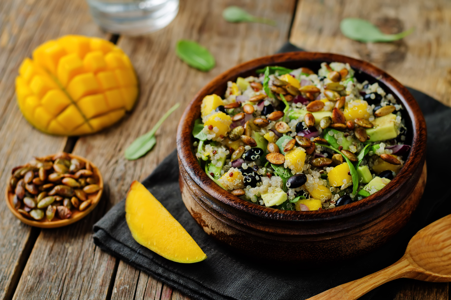 a bowl of mango and black bean salad with a cut mango on the table next to the bowl