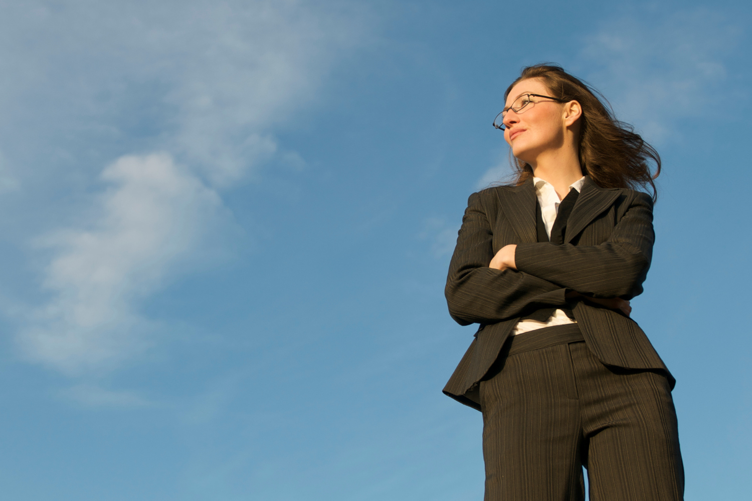 a woman in a business suit standing with her arms crossed