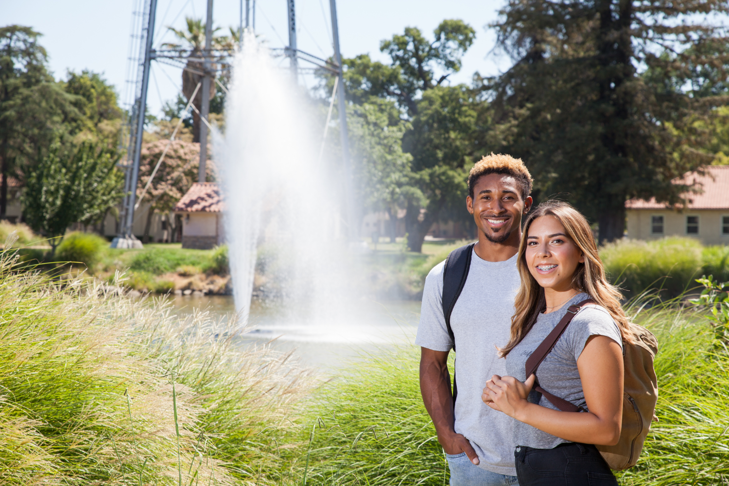 Two Stockton students smiling. Water fountain in the background.