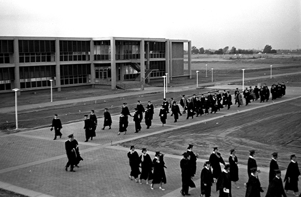 Graduates march in the Quad past the Library building during 1965 Commencement ceremonies.