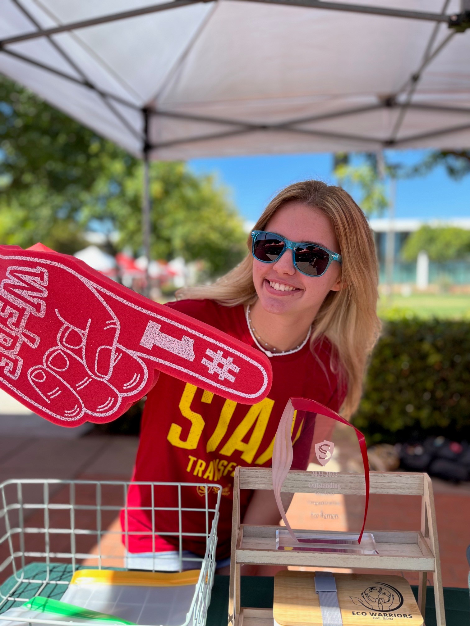 student holding foam finger in quad