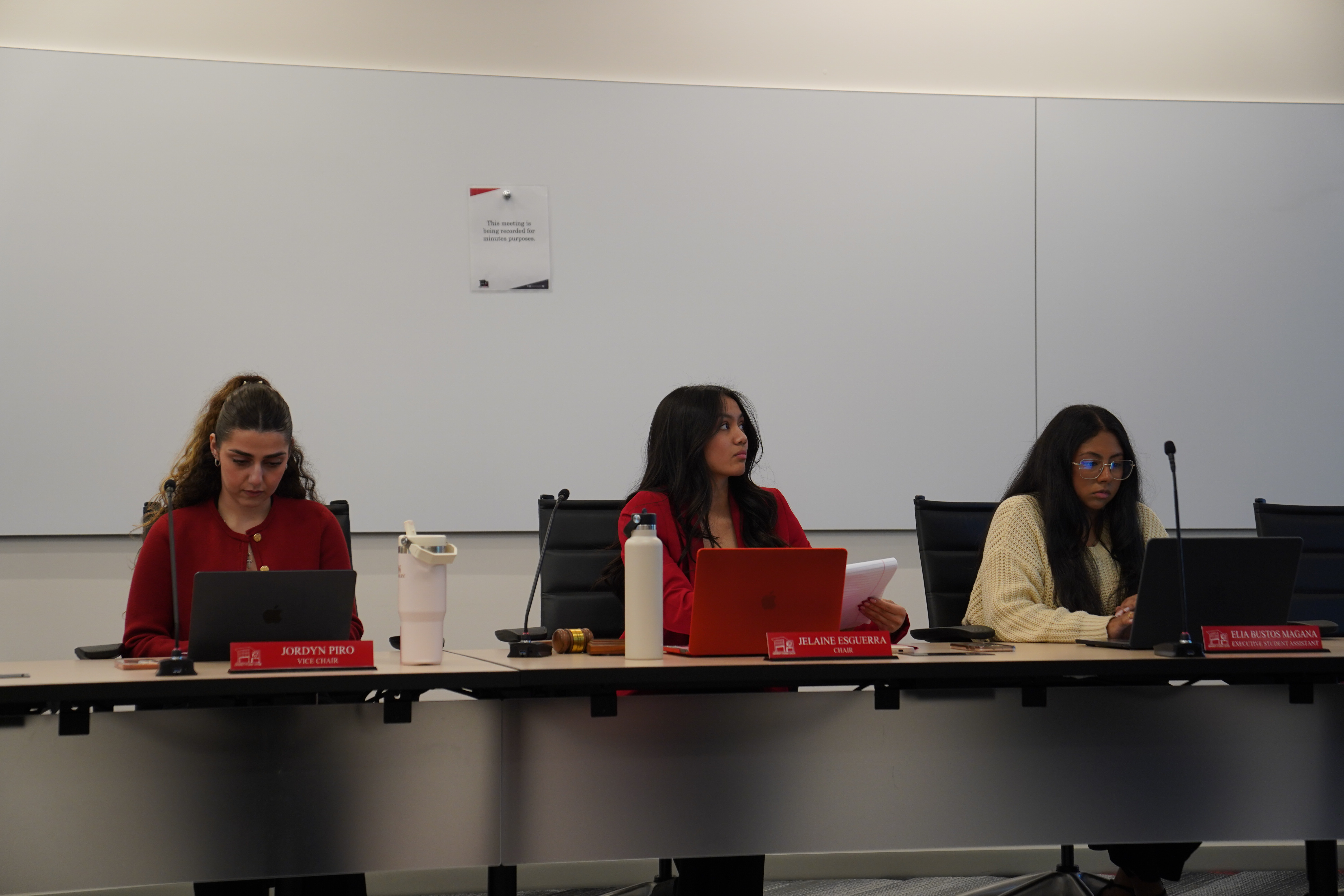 Students sitting behind table with laptops out in a meeting