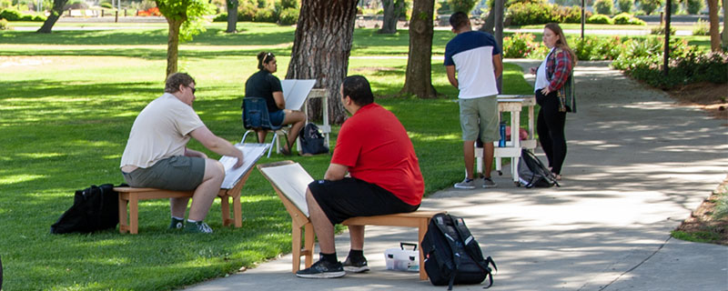 Art students work outside drawing from nature.