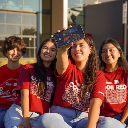 Students sitting on the ground taking a photo