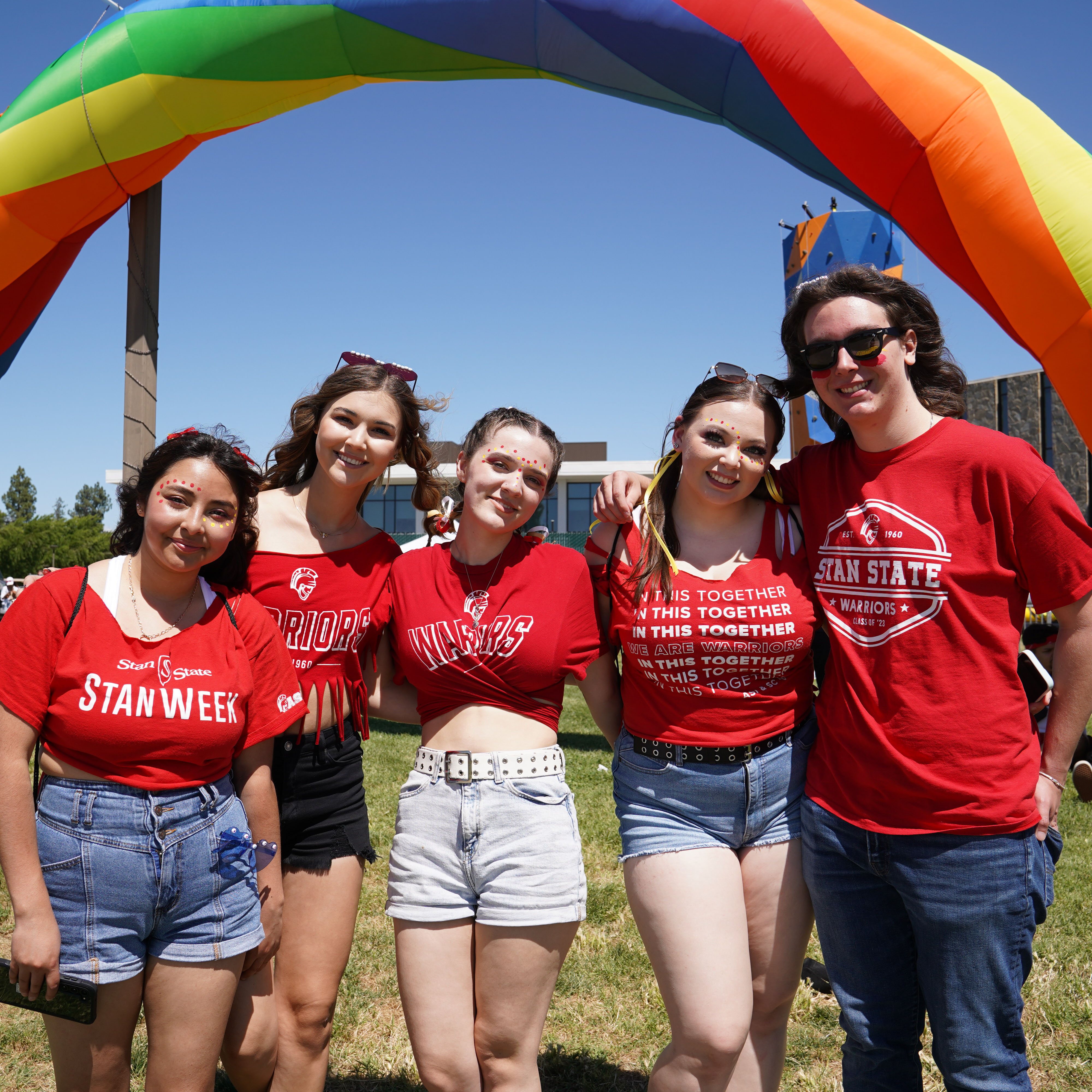 Students posing in front of rainbow arch