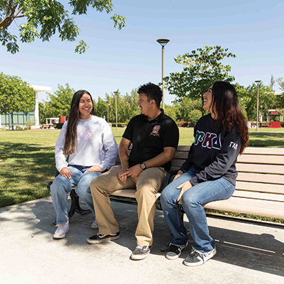 Students seated on an outdoor bench at campus.