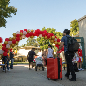 Students approaching the Housing Residential Village with luggage and boxes during move-in day