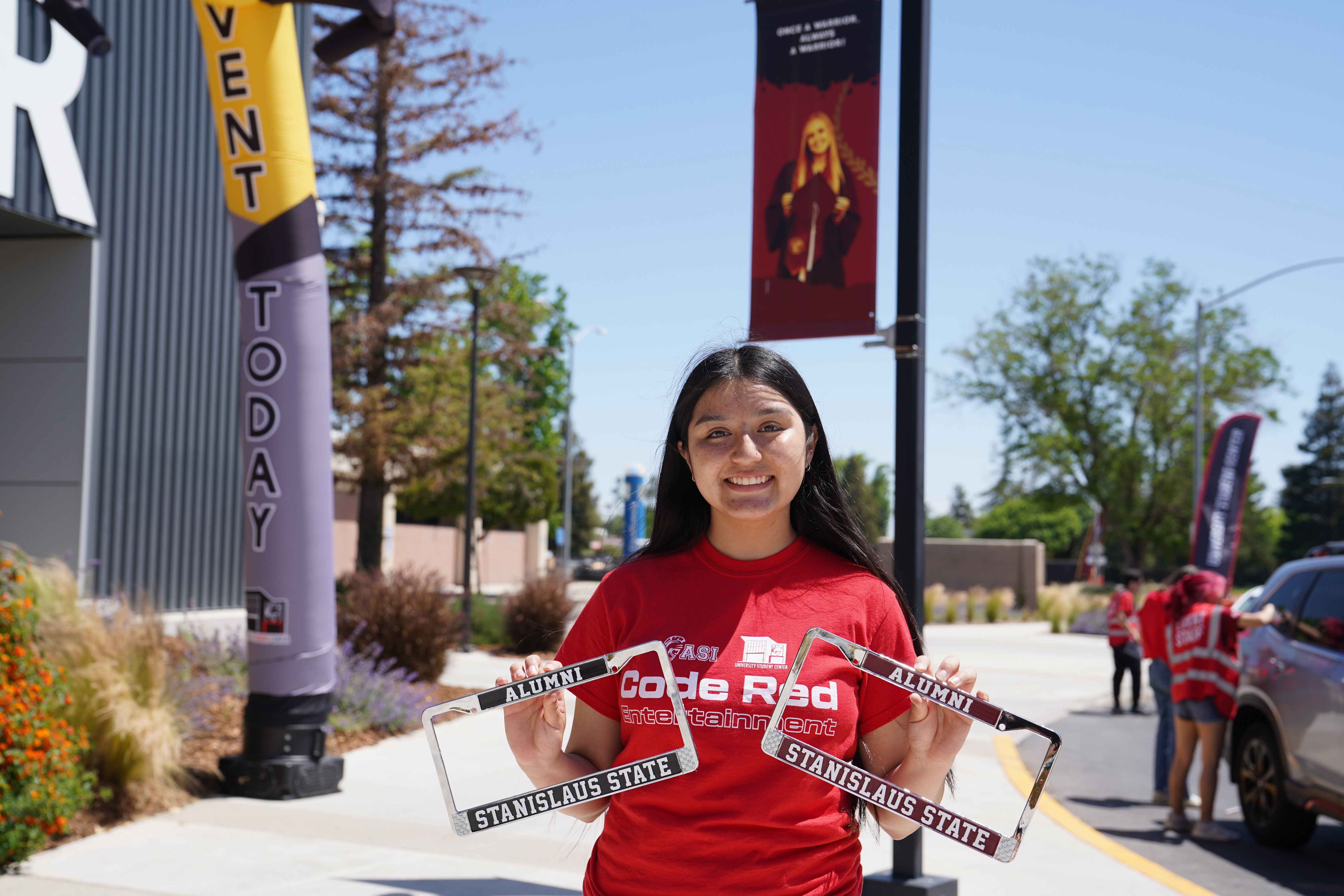 Student holding 2 Stan State license plate frames