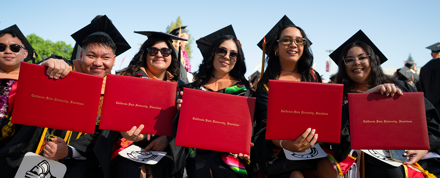 grads holding up their degree covers