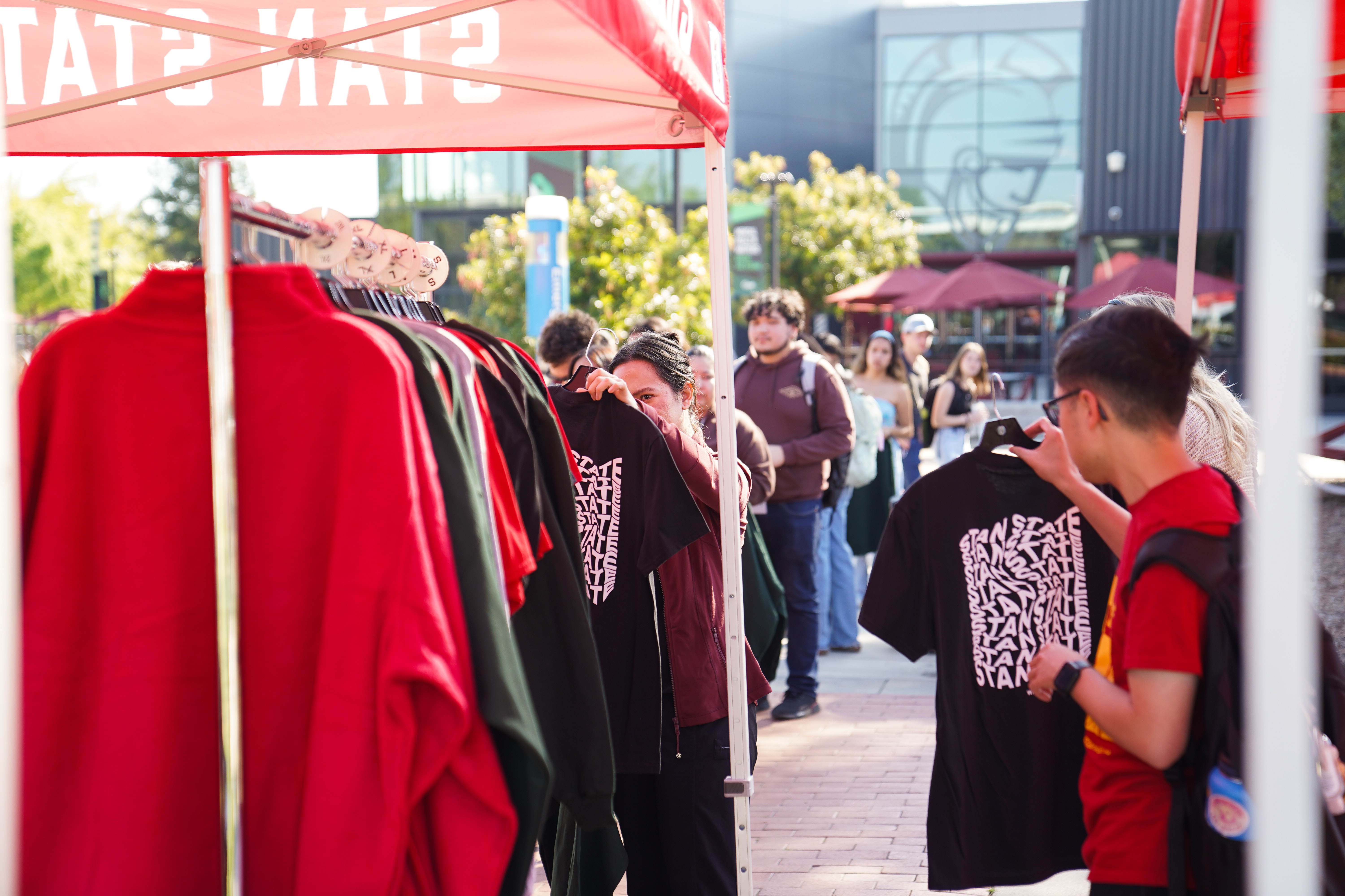 Student looking at Stan State merch clothing rack in the quad