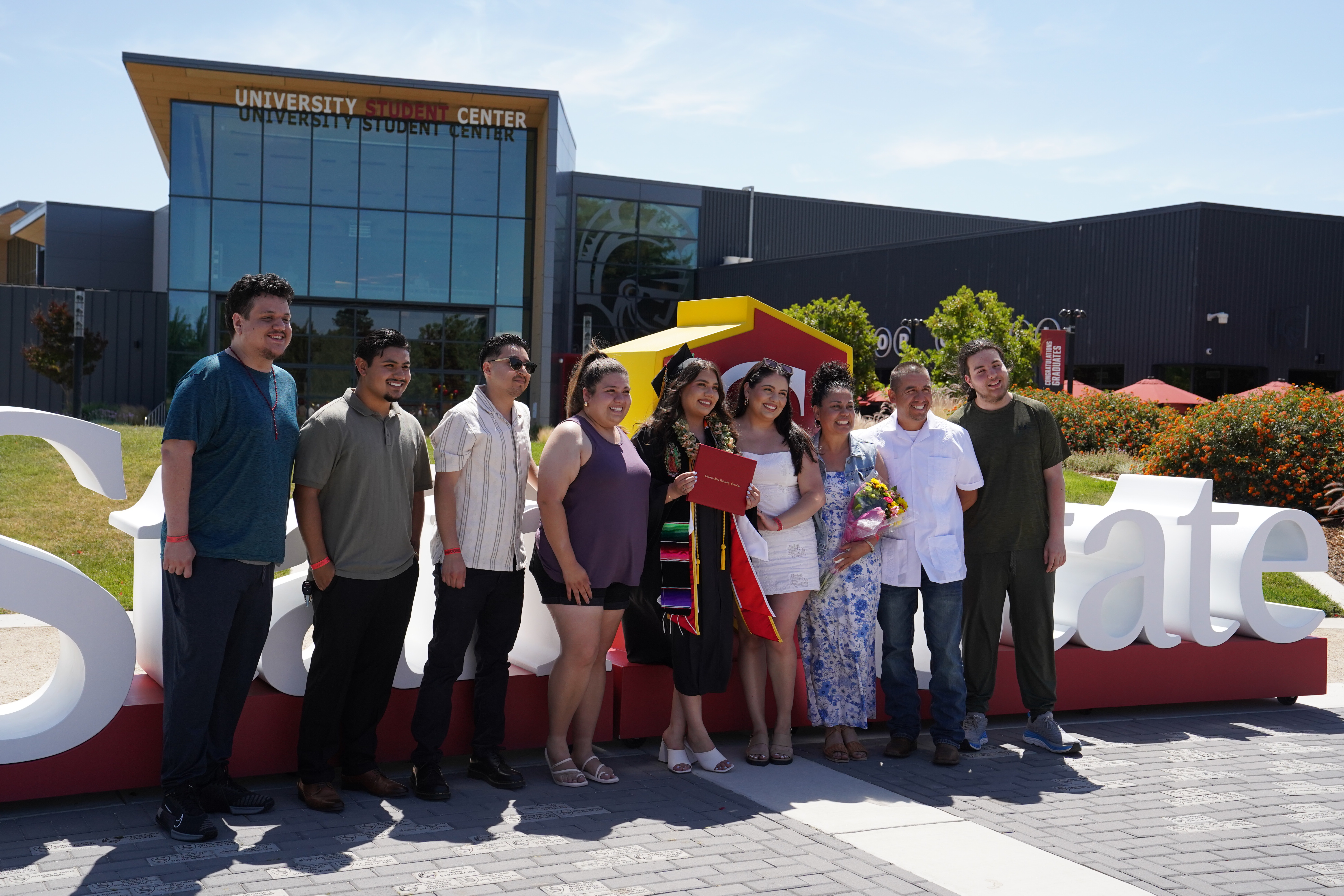 Group of SC graduating students in front of Stan State foam letters