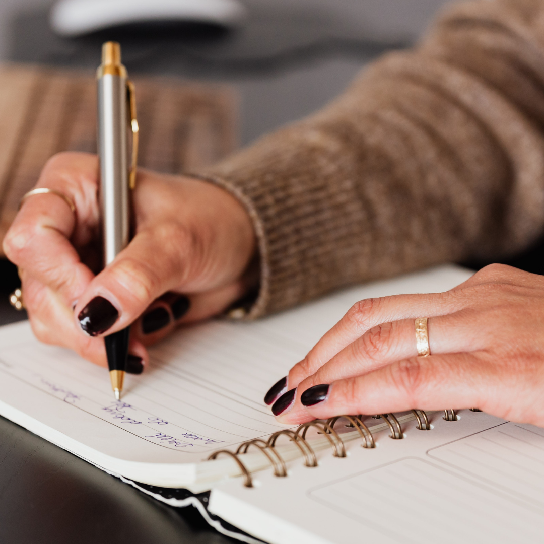 Person writing a letter into a notebook.