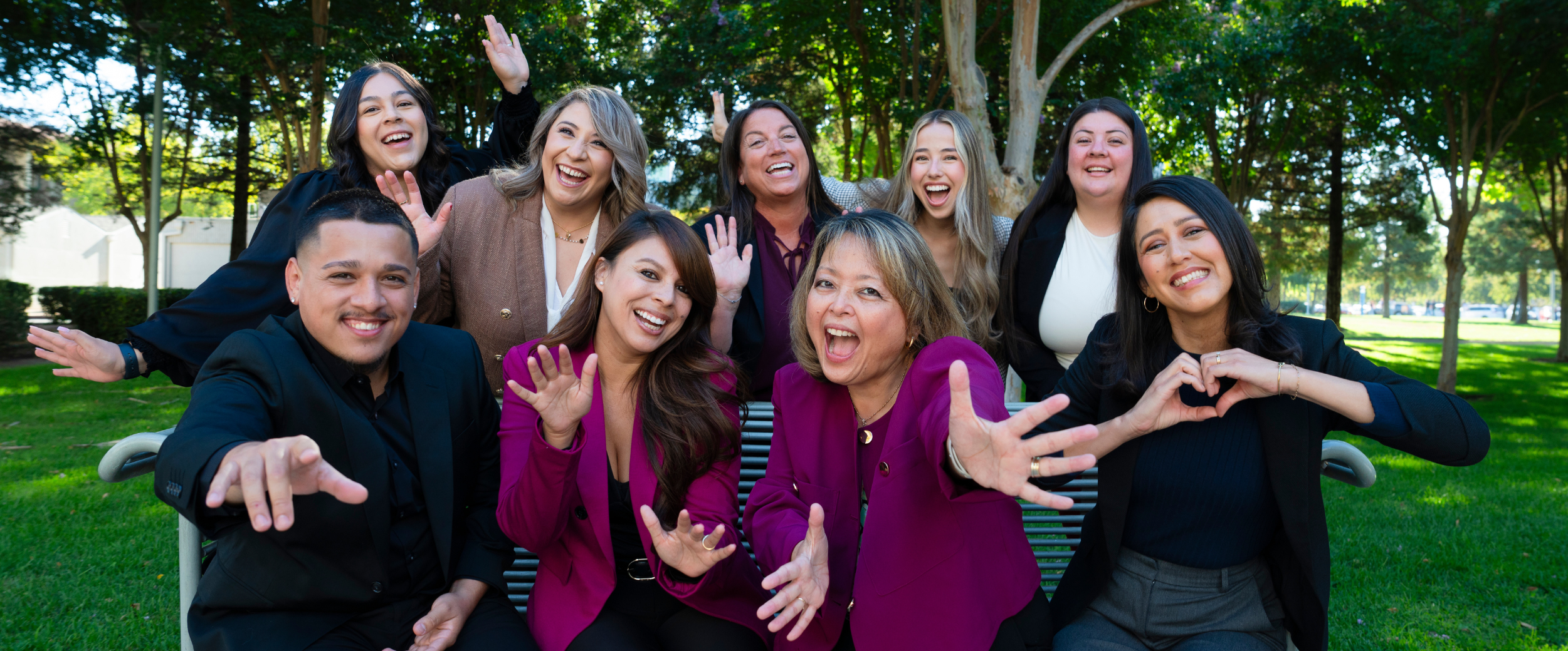 Undergraduate Recruitment team smiling and waving on campus, welcoming future students.