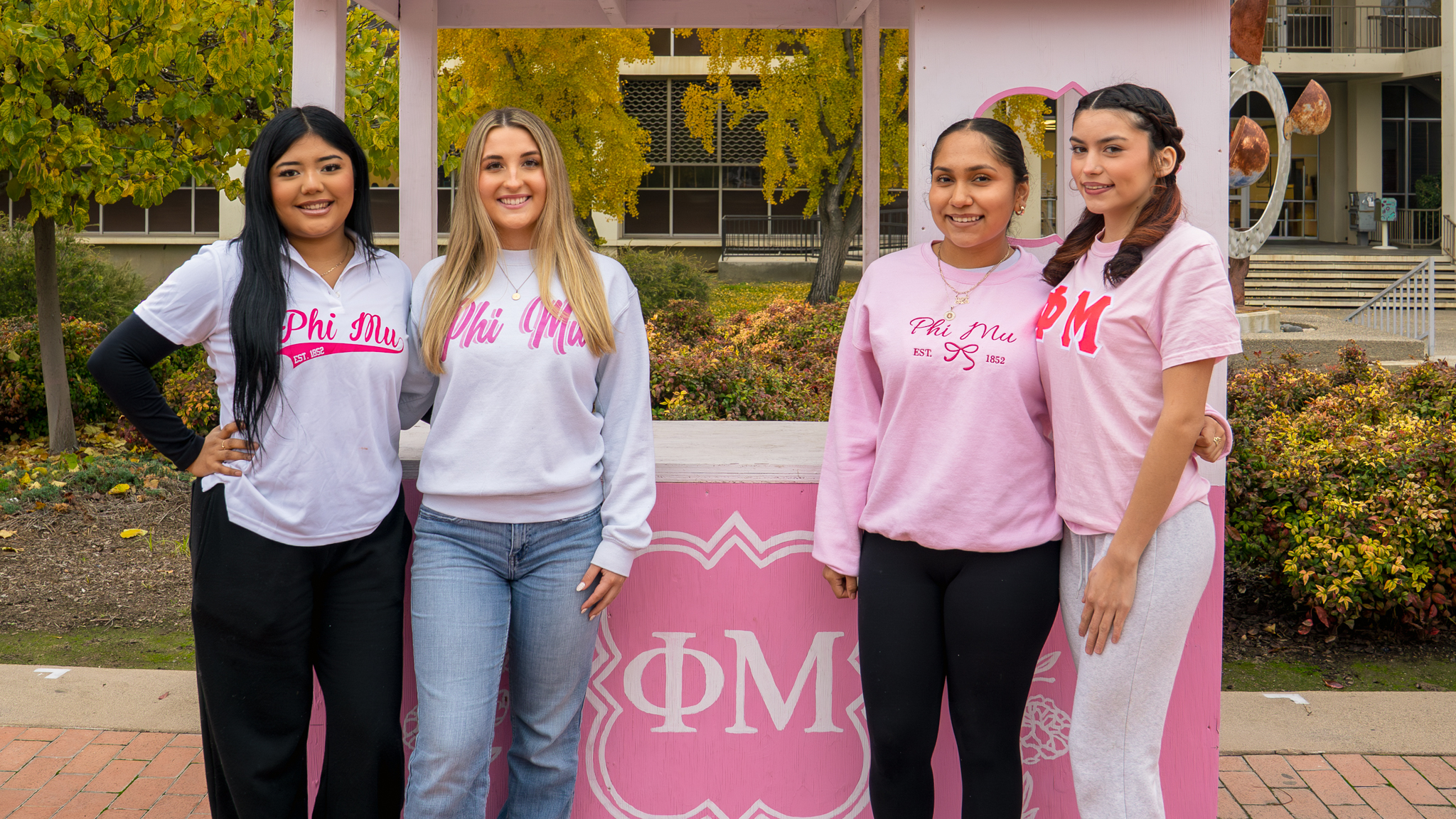 4 students from Phi Mu Sorority posing in front of their organization's booth