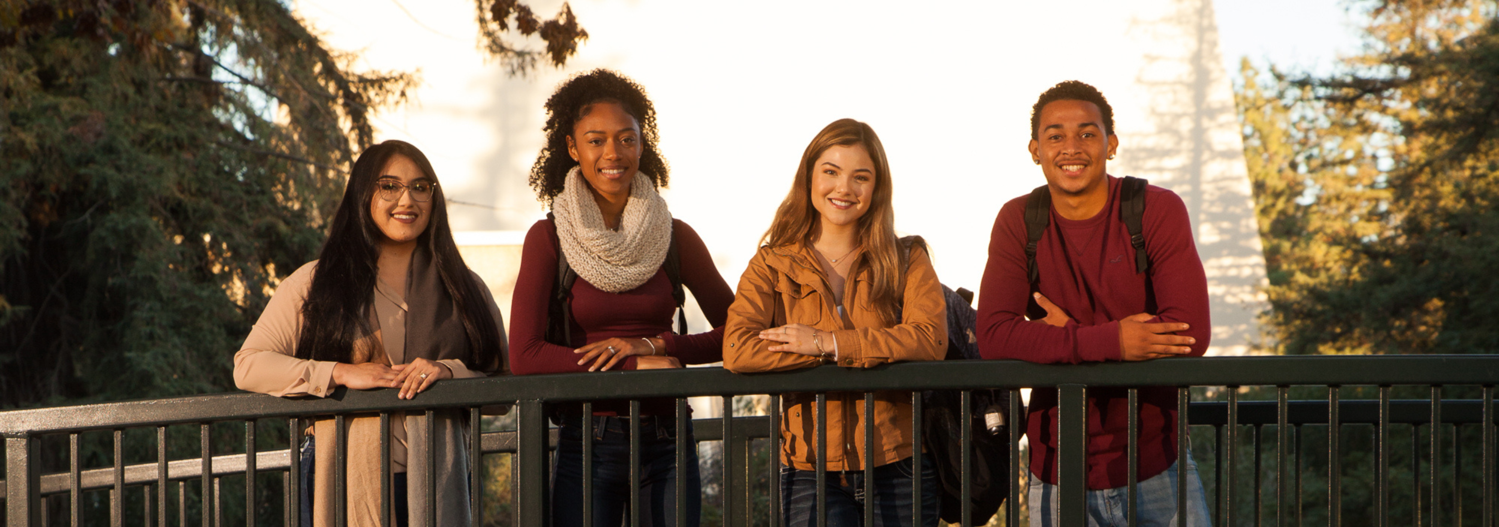 Four students posing for a photo on a bridge at Stan State.