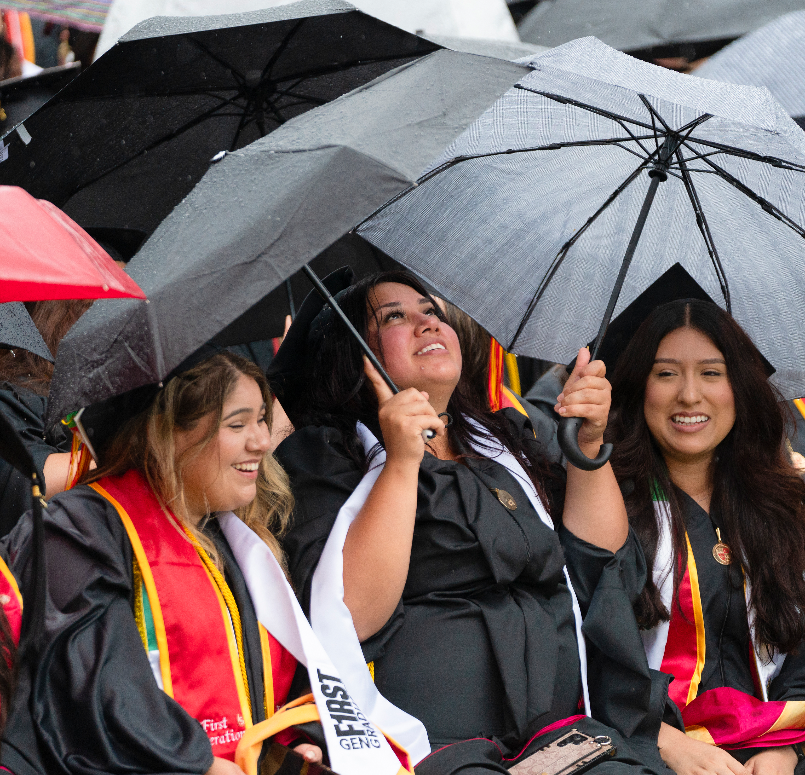 Graduates with umbrellas seated in their regalia at Commencement