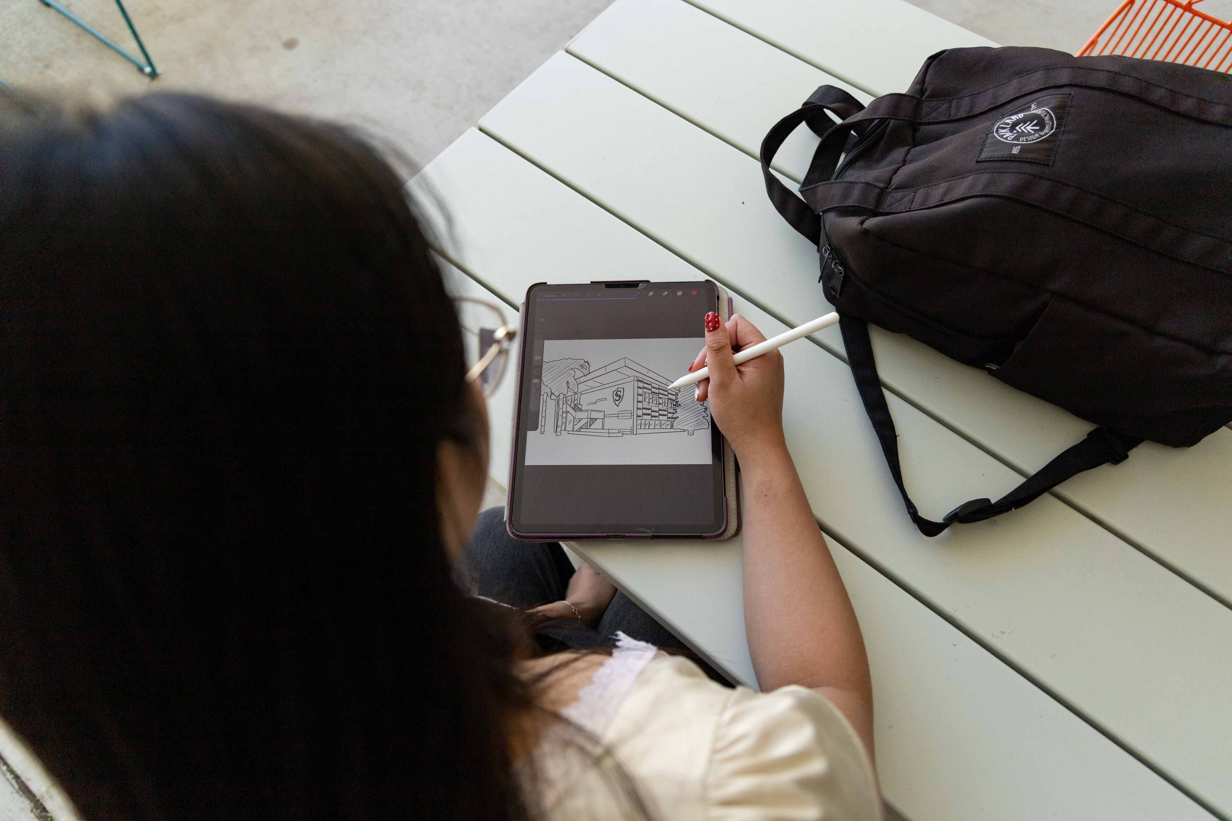 Looking over the shoulder of a student creating artwork on a tablet