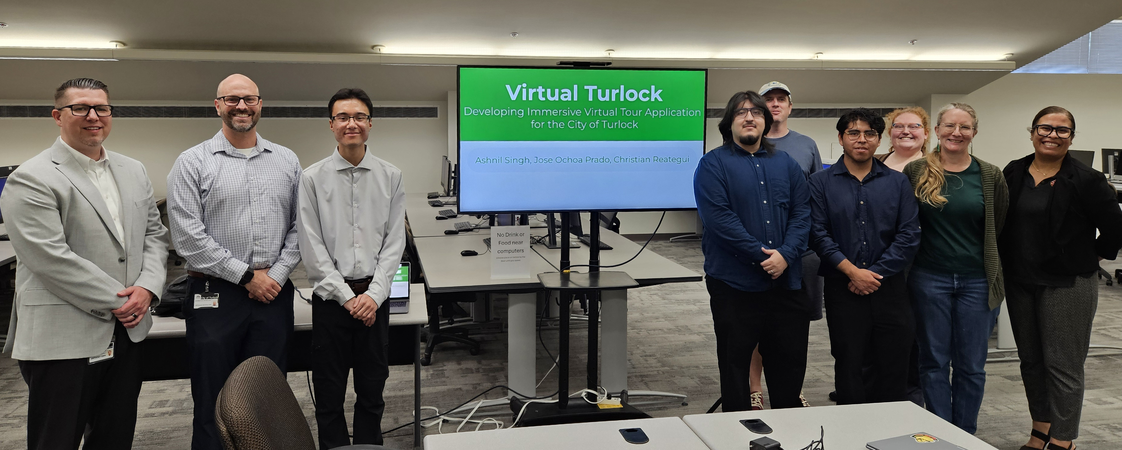Students, staff and city partners stand together in a computer lab