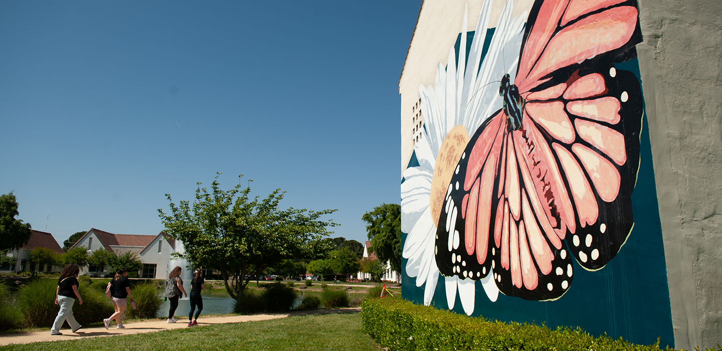 Students walk near a mural of a Monarch butterfly. 