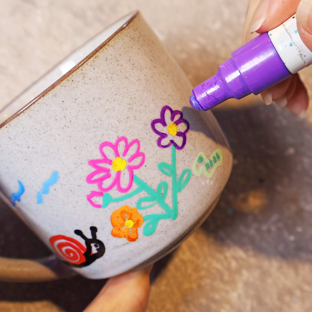 Person drawing on a cup with an art marker.