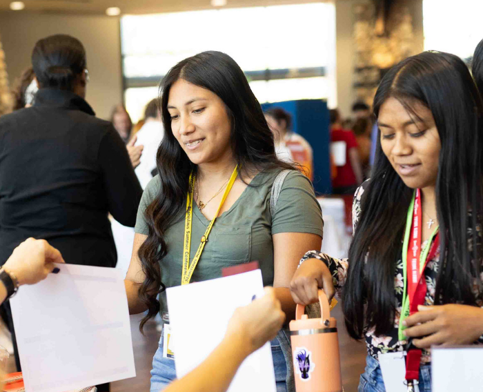 Students speaking with staff at a campus support table.