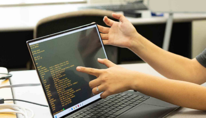 Student pointing to code on a laptop screen