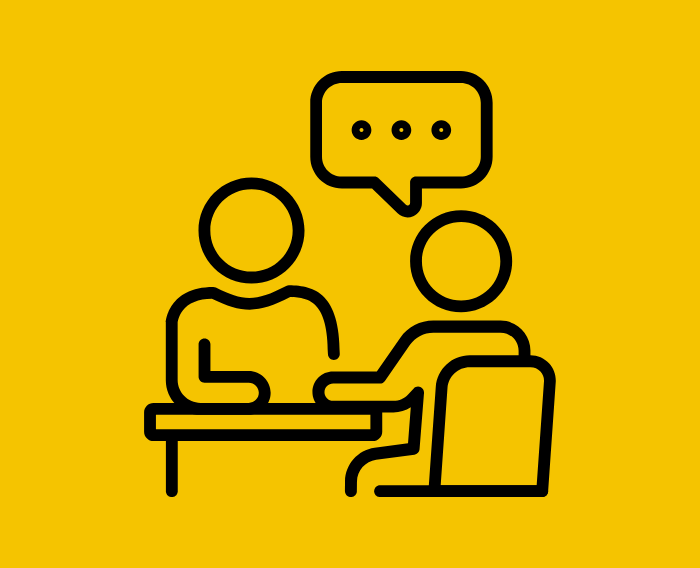 Icon of two people seated across from each other at a table, with a speech bubble above them indicating a conversation or advising session.