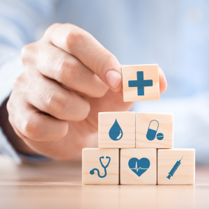 A hand stacking blocks with health-themed icons on them