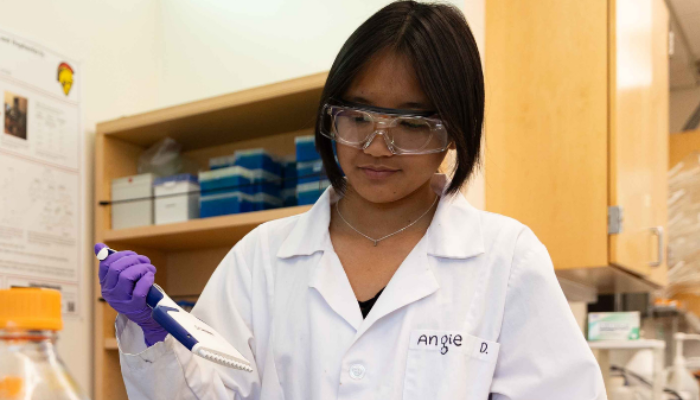 A chemistry student is seen holding lab equipment