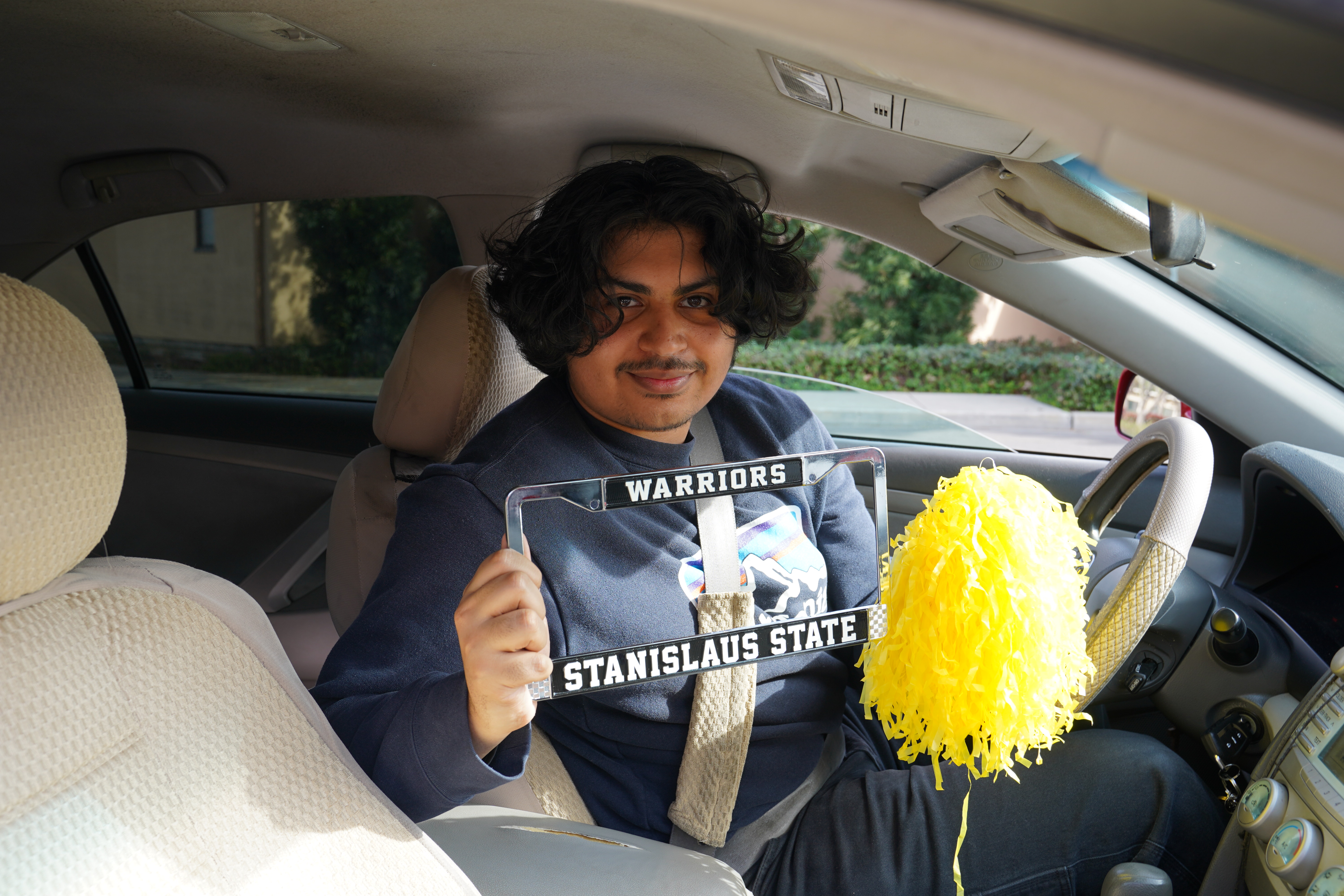 Student holding up Stan State license plate frame