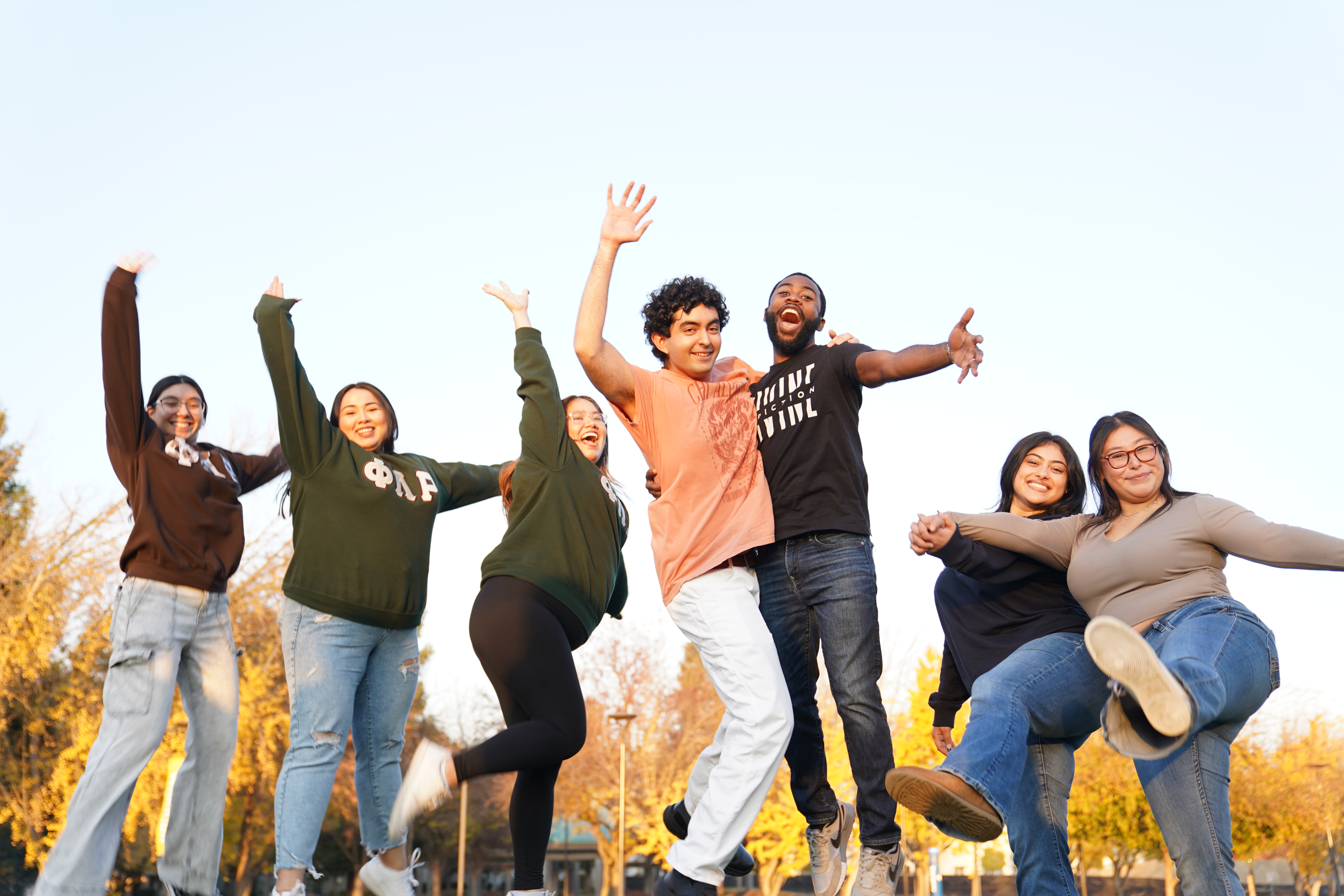 Group of students jumping and cheering outdoors together