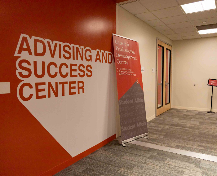 Interior entrance to the Advising and Success Center with large wall signage and a hallway leading into the office.