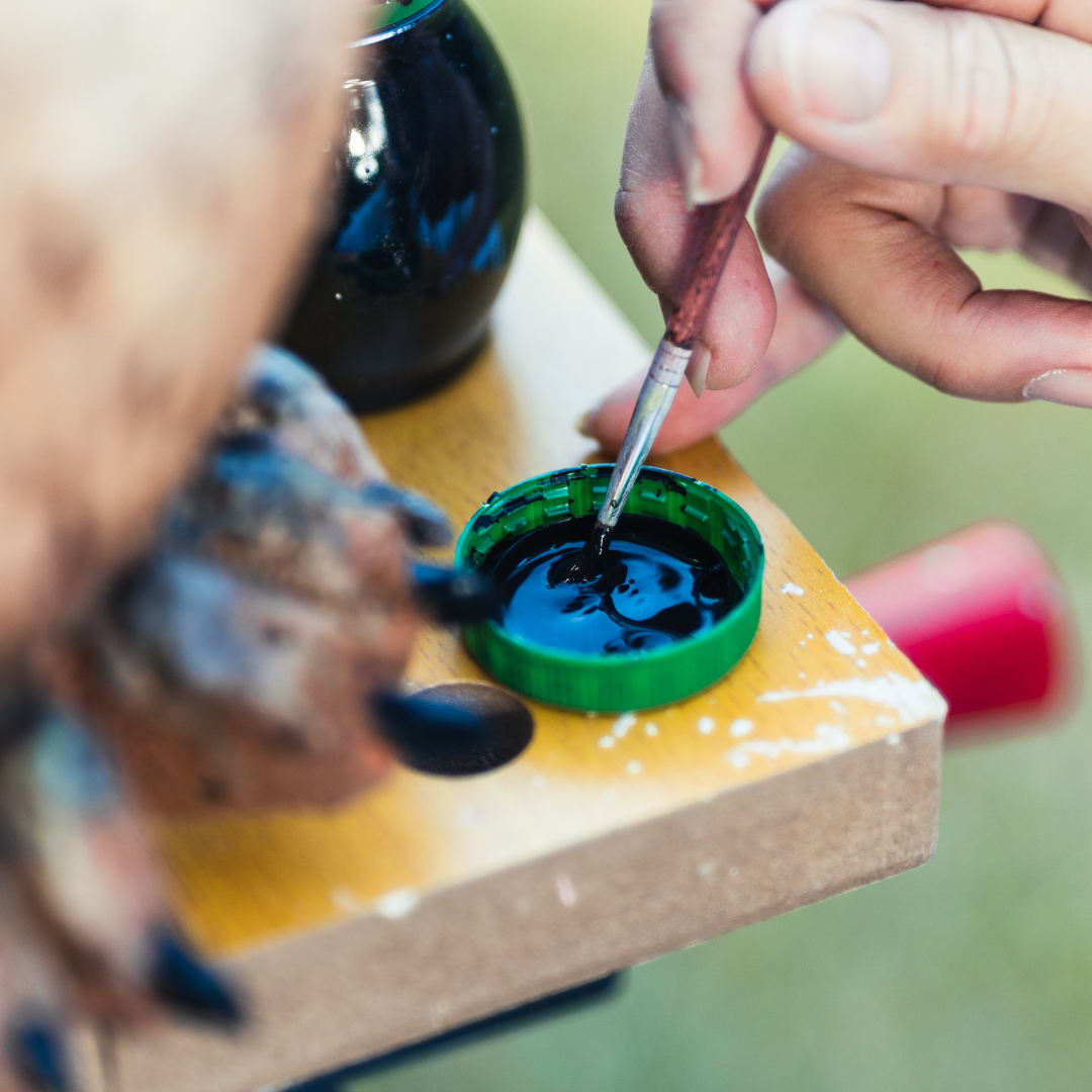A person dipping their brush into paint.