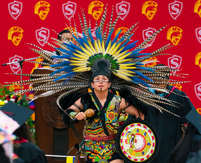 A Mexica dancer performs in traditional ceremonial attire at the graduation celebration