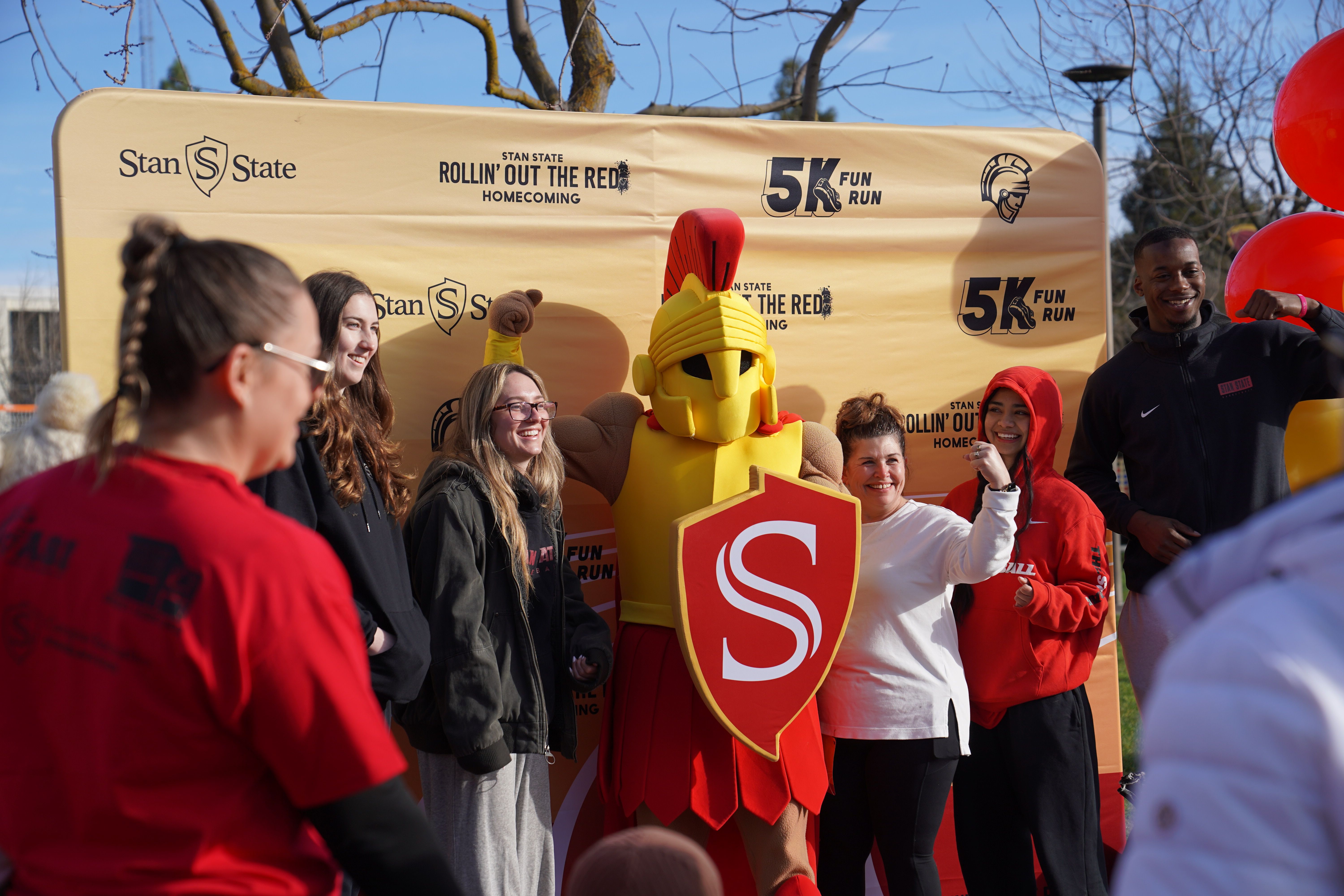 Titus and students posing in front of the 5k Fun Run Backdrop