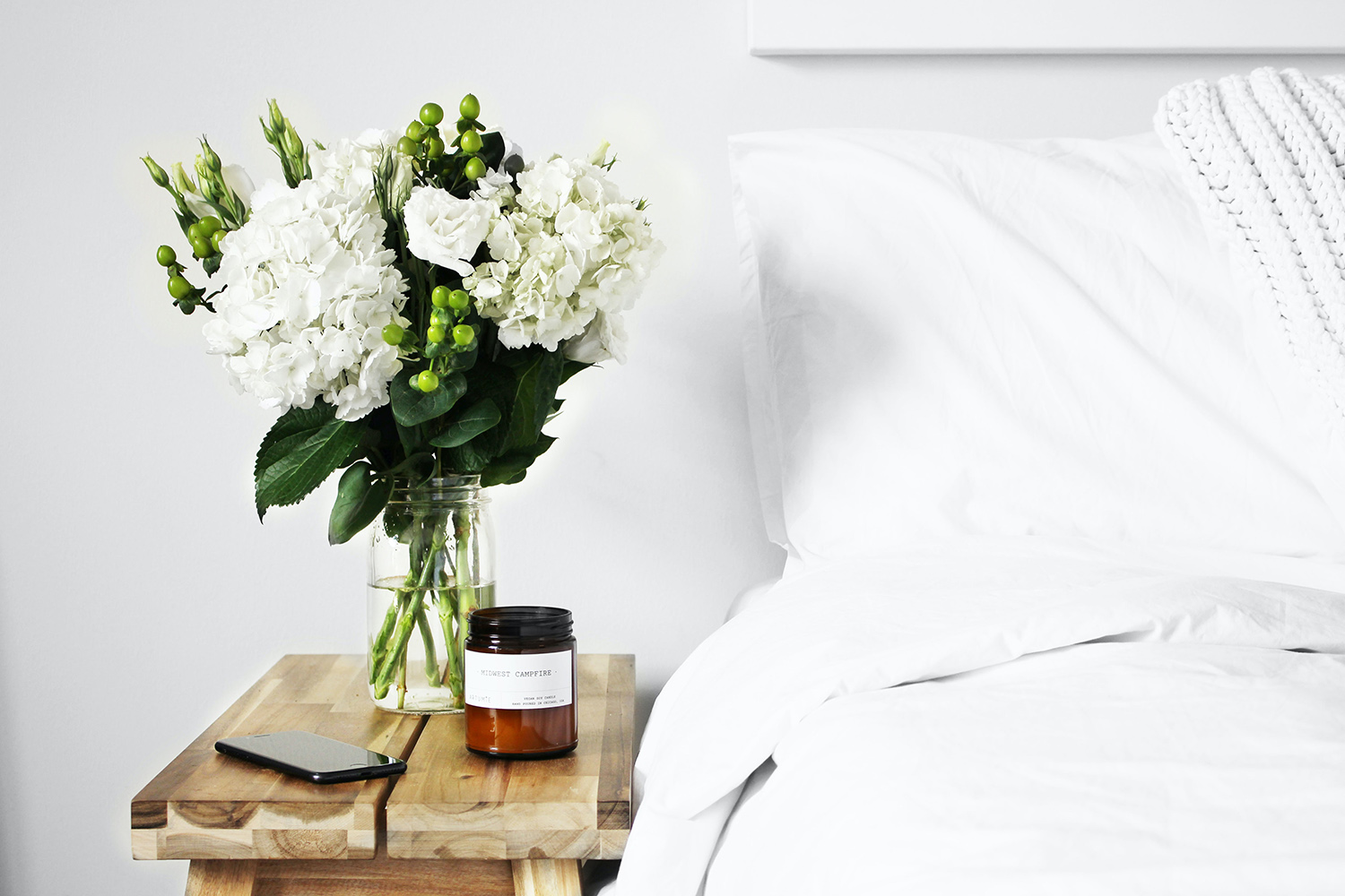 Bed and white flowers on a nightstand.